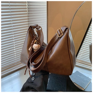 Detail of dark brown leather hobo bag with zipper closure and baseball pendant