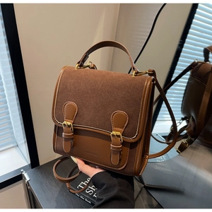 Detail of vintage brown suede messenger bag with dual buckles and embossed brand logo