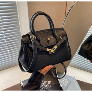 Detailed view of black lychee grain leather handbag with gold-tone hardware and buckle