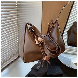 Detail of soft dark brown PU leather tote with ruched texture and baseball charm
