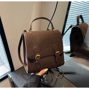 Detailed view of dark brown vintage satchel with double buckles and matte leather texture