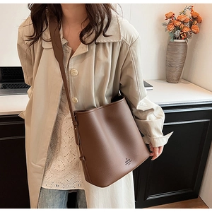 Deep brown bucket bag with adjustable wide strap shown in a stylish interior lifestyle setting