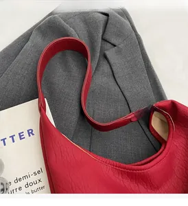 Detail of dark red leather tote bag showing textured grain on a grey blazer background
