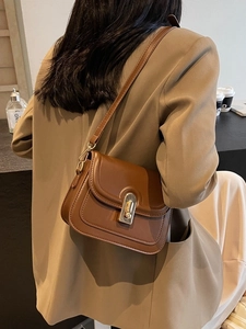 Sac bandoulière rétro en cuir marron avec fermoir doré porté par un mannequin chic