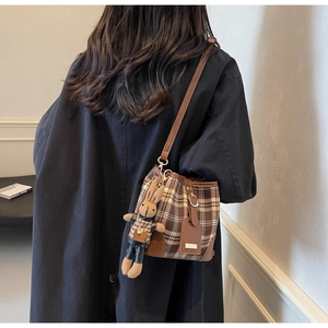Bruine en beige geruite emmertas met konijnenhanger getoond als een crossbody model