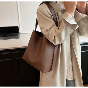 Close-up of brown pebbled leather bucket bag with embossed logo and adjustable strap
