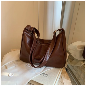 Detail of dark brown vintage hobo bag with glossy leather texture on a white blazer
