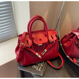 Detailed view of red lychee grain leather handbag with gold twist-lock and top handles