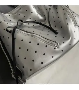 Close-up of metallic silver tote bag with black polka dots and soft fabric texture