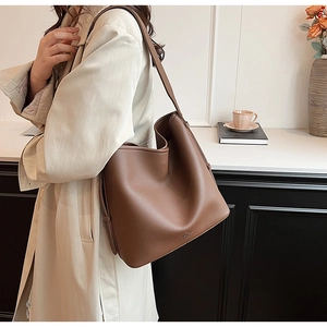 Close-up of brown lychee leather hobo bag with sleek texture and metallic logo detail