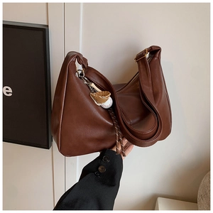 Detailed close-up of dark brown faux leather hobo bag with baseball themed charms