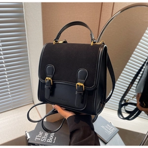 Close-up of retro black satchel bag featuring dual buckles and textured suede leather detail