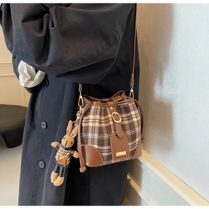 Detail van geruite emmer tas met trekkoord sluiting en een schattige konijn hanger