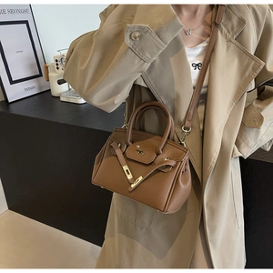 Close-up of brown litchi pattern leather bag with golden metal clasp and handle