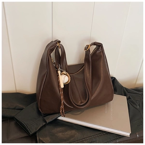 Detail of dark brown leather hobo bag with a stylish baseball charm and spacious design