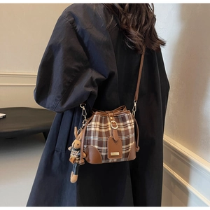 Detail van vintage bruine geruite emmertas met leren riem en schattige konijnenhanger