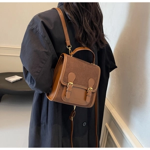 Detail of vintage brown leather backpack with dual gold buckles and suede flap cover