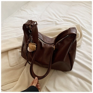 Detailed close-up of dark brown faux leather tote with zipper and baseball charm