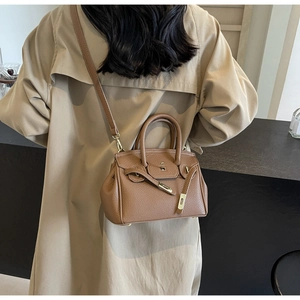 Brown lychee leather handbag with gold lock shown with khaki trench coat in macro detail