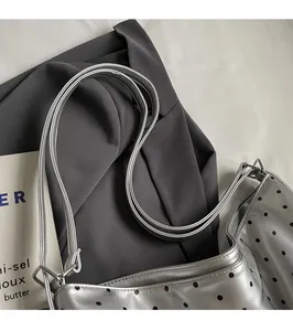 Detail of silver polka dot tote bag showing thin straps and sleek metallic texture