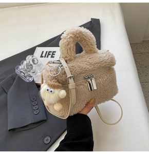 Detail of beige faux shearling handbag with metal zippers and cute plush charm