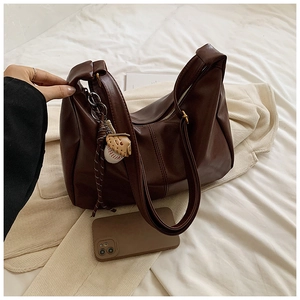 Detail of dark brown tote bag showing matte leather texture and baseball glove charm