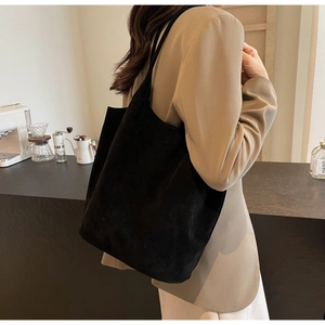 Detail of a minimalist black PU suede tote bag with slim shoulder straps for daily use