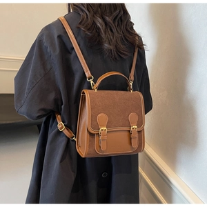 Brown vintage college style backpack with double metal buckles on a female model back