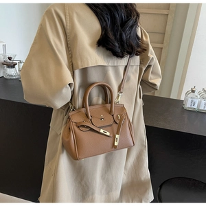 Detail of brown lychee leather handbag featuring gold metal hardware and stitching
