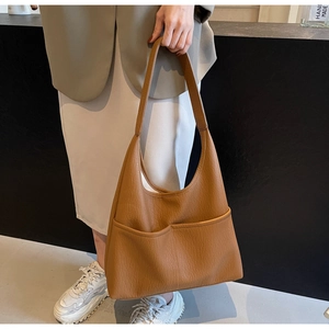 Detail of large caramel tote bag featuring textured lychee leather and front pockets