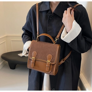 Close-up of vintage brown dual-texture shoulder bag featuring golden buckles and brand logo