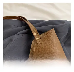 Close-up of litchi texture brown leather handle and gold rivet hardware of the tote bag