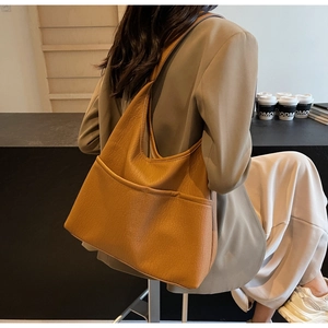 Detail of caramel brown tote bag showing leather texture and front pocket design