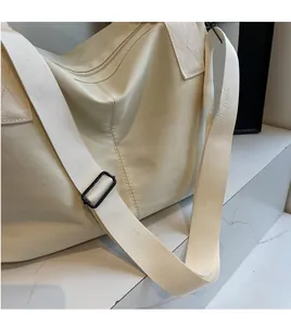Detail of adjustable wide woven shoulder strap on a beige nylon crossbody tote bag