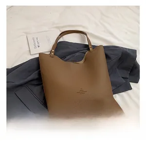 Close-up of brown lychee grain leather tote with gold rivets and metallic logo text