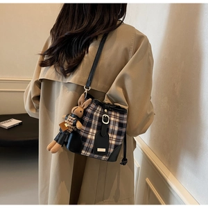 Detail van geruite emmer tas met lederen bekleding en schattige konijnen knuffel hanger