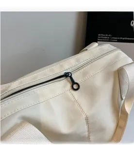 Detail of a smooth black circular zipper and textured nylon fabric on a white tote bag