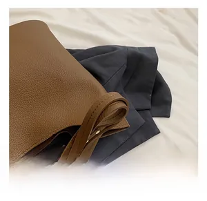 Detail of wide caramel lychee leather strap with fine edge stitching and metal hardware