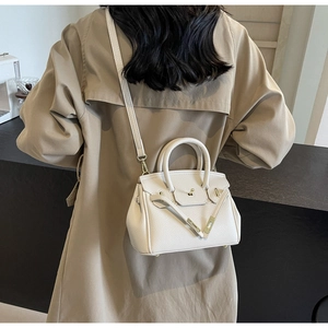 Detail showing the cream lychee grain leather texture and light gold lock on the bag