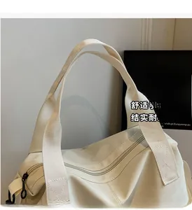 Detail of the reinforced woven handles and zip closure on this cream canvas tote bag