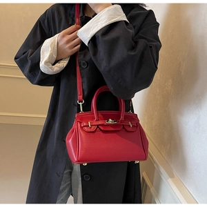 Close-up of red pebbled leather handbag with gold buckle and adjustable shoulder strap
