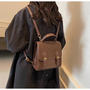 Detailed back view of vintage dark brown faux leather satchel with double metal buckles
