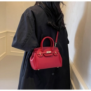 Rear view of a model wearing a luxury red pebble leather handbag with gold hardware