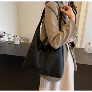 Detail of black large capacity hobo tote bag featuring side pockets and soft leather texture