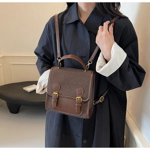 Detail of vintage brown messenger bag showing dual buckle straps and leather texture