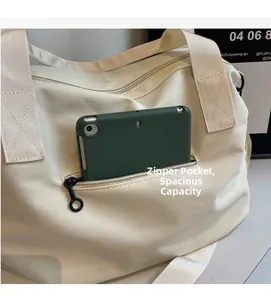 Detail of cream tote bag front zipper pocket holding a tablet to show high capacity