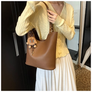Detail of brown litchi pattern leather bucket bag with cute plush lion pendant
