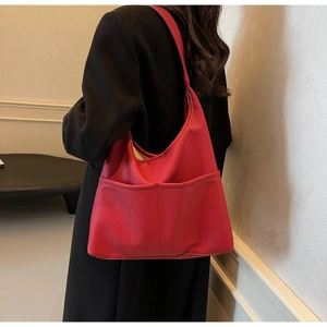 Detail of red pebbled leather tote bag with functional pockets worn by model