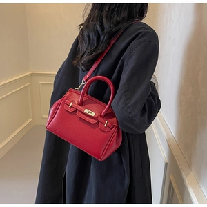 Detailed view of red pebble leather handbag with classic metal twist lock and strap