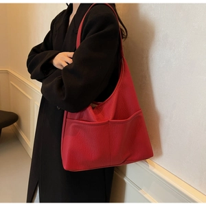 Detail of red oversized hobo bag in lychee texture PU leather carried by model